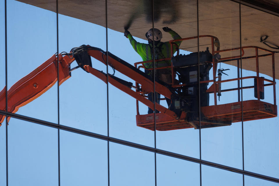 A construction worker works under the shade of a building while protecting himself from the sun and heat during the construction of a large office building in the biotech sector in San Diego, California, US, July 2, 2024. REUTERS/Mike Blake