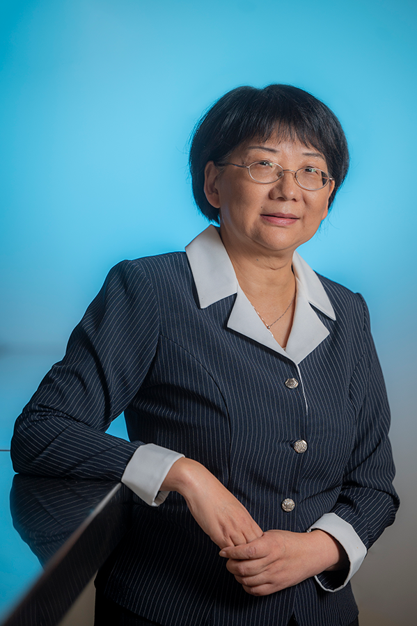 A woman in a business suit leans over a table.